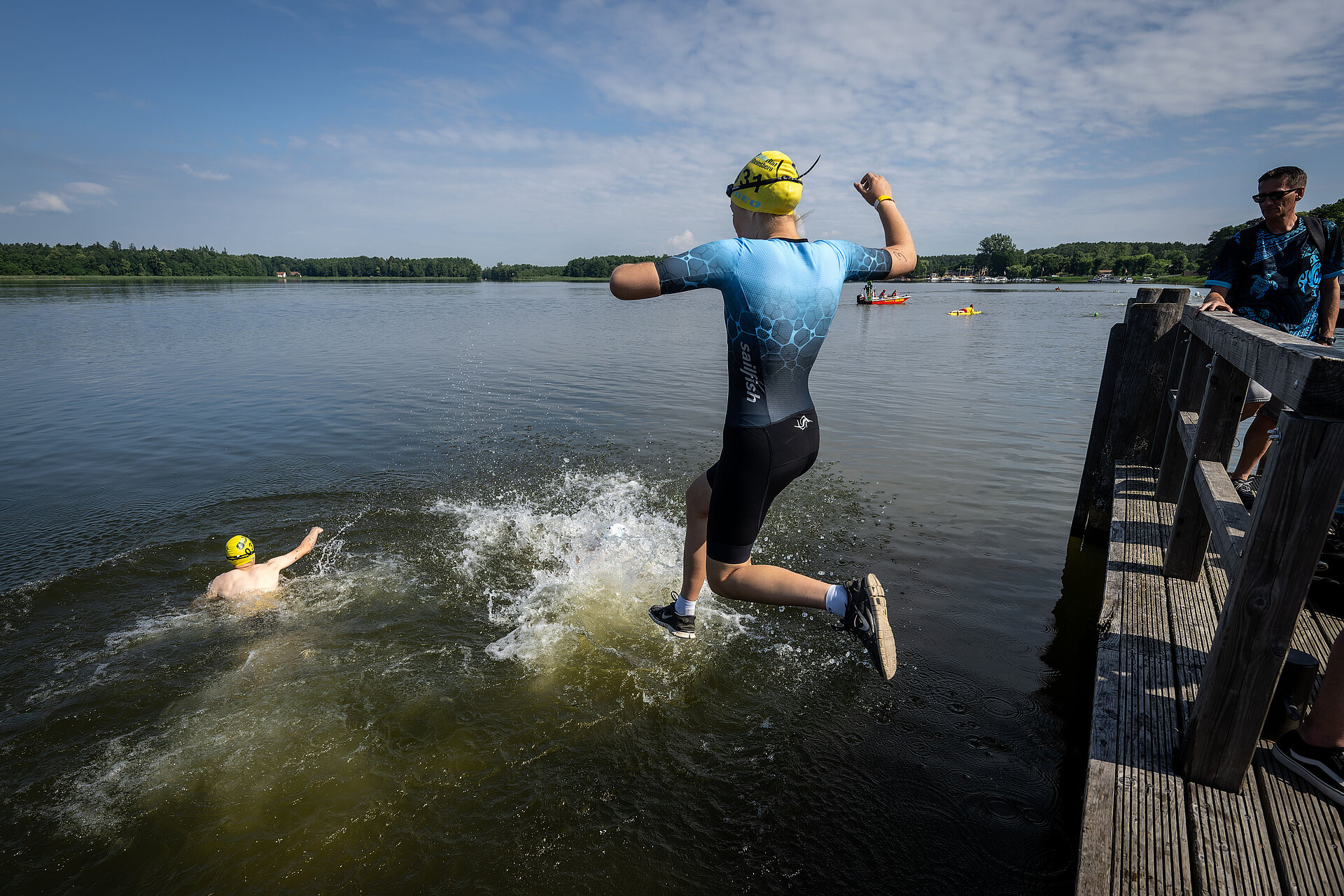 Participant in the SwimRun Rheinsberg jumping into the water where someone else is already swimming.